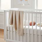 Babydeken aan wieg met baby